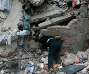Un trabajador busca víctimas entre los escombros de un edificio derrumbado tras el terremoto. Foto AP