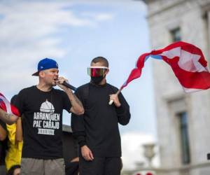 Los artistas puertorriqueños René Pérez “Residente” y Benito Antonio Martinez Ocasio “Bad Bunny” avivan a una multitud frente al capitolio puertorriqueño previo a una manifestación contra el gobernador Ricardo Roselló. Foto AP