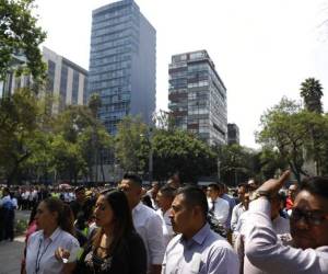 Trabajadores evacuados de un edificio federal después de un sismo aguardan en la acera de la avenida Paseo de la Reforma, en la Ciudad de México. (Foto: AP)