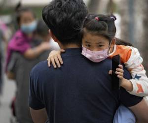 Varias personas llevan a sus niños a un kínder, con mascarillas para protegerse del coronavirus, el 9 de junio del 2021, en Beijing. (AP Foto/Andy Wong)