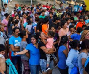 En esta imagen de archivo del 30 de agosto de 2019, migrantes, muchos de ellos devueltos a México por la política migratoria del entonces presidente estadounidense Donald Trump, hacen fila para recibir alimentos en un campamento en el puente internacional, en Matamoros, México. Foto: AP