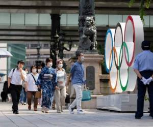 Peatones frente a los anillos olímpicos instalados en en el puente Nippon Bashi en Tokio, el jueves 15 de julio de 2021. Foto: AP