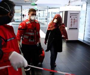 Una mujer con mascarilla de protección es evacuada de la zona de seguridad donde un autobús procedente de Milán. Foto AFP