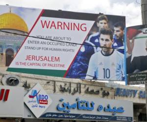 Un cartel erigido en una calle principal en la ciudad cisjordana de Hebrón junto a un retrato del presidente palestino Mahmud Abbas y Leo Messi que boicoteó el partido. Foto: AFP