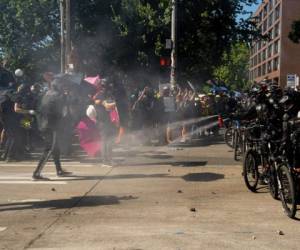 La policía antidisturbios se enfrentó a los manifestantes, algunos de los cuales levantaron paraguas para evitar ser alcanzados por el gas pimienta. Foto: AFP