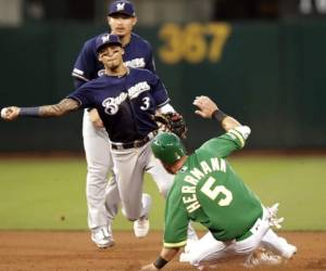 El jugador de los Cerveceros de Milwaukee Orlando Arcia (3) lanza ante Chris Herrmann (derecha), de los Atléticos de Oakland, para completar una doble matanza con Chad Pinder, en el cuarto inning del juego de la MLB que enfrentó a ambos equipos. Foto:AP