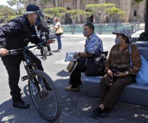 Un oficial de la Policía Municipal pide a las personas en una plaza que abandonen el lugar ya que no se permite estar en espacios públicos en el estado de Jalisco como medida preventiva contra la propagación del nuevo coronavirus, Covid-19, en Guadalajara, México. AFP.