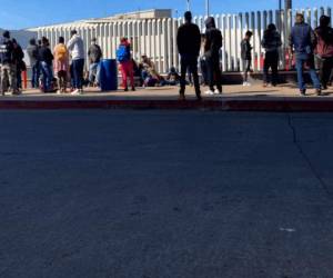 En esta imagen del miércoles 17 de febrero de 2021, migrantes en espera de noticias en un cruce fronterizo en Tijuana, México. (AP Foto/Elliot Spagat).
