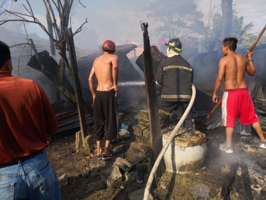 Miembros del Cuerpo de Bomberos de Honduras tratan de apagar las llamas en la vivienda completamente destruida.
