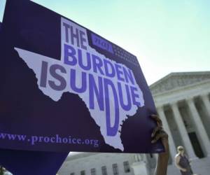 Un activista por los derechos del aborto sostiene pancartas fuera de la Corte Suprema de los EE. UU. Antes de que la Corte revoque una ley de Texas que impone restricciones a las clínicas de aborto en Washington, DC Un juez federal de los Estados Unidos. Foto: Agencia AFP.