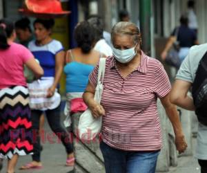 Una señora de la tercera edad circula por el centro de Tegucigalpa con una mascarilla. Foto: Marvin Salgado / EL HERALDO.