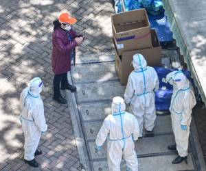 Se ve a trabajadores con equipo de protección junto a bolsas de verduras entregadas por el gobierno local para los residentes durante la segunda etapa de un cierre de covid-19 en Shanghái el 2 de abril de 2022.