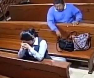 Momento en el que el hombre saca el celular de la cartera de la feligresa. Foto: Captura.
