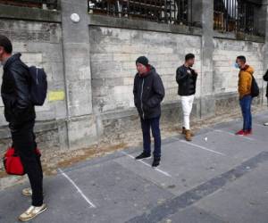 Varias personas hacen cola, guardando distancia, para recibir comida en un centro para indigentes y migrantes de París. Foto: AP.