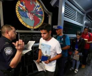 El cubano Abel Oset hijo, al centro, y su padre Abel Oset, detrás de él, muestran sus identificaciones a un agente de la Oficina de Aduanas y Protección Fronteriza estadounidense antes de su cita para solicitar asilo en Estados Unidos. Foto: AP.