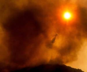 Un helicóptero arroja agua mientras combate un incendio forestal en Salinas, California. (AP Foto/Noah Berger).