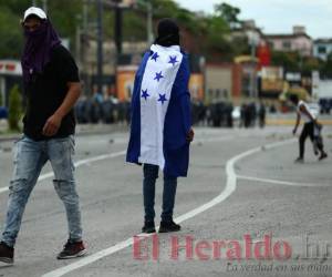 En el segundo día de paro nacional convocado por los médicos y maestros, varios encapuchados, que intentaron bloquear el paso en el bulevar Centroamérica, se enfrentaron con las autoridades policiales este viernes. Fotos: Emilio Flores / EL HERALDO.
