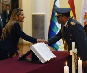 La presidenta interina de Bolivia, Jeanine Anez, se da la mano con el nuevo comandante en jefe de las Fuerzas Armadas, el general del ejército Carlos Orellana, en el palacio presidencial de Quemado en La Paz. Foto: Agencia AFP.