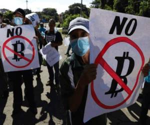 Agricultores sostienen carteles con mensajes contra la adopción del bitcoin como moneda de curso legal durante una protesta a lo largo de la Carretera Panamericana en San Vicente, El Salvador, el martes 7 de septiembre de 2021. (AP Foto/Salvador Meléndez).