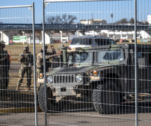 Miembros de la Guardia Nacional de Texas vigilan detrás de una cerca en Shelby Park el 3 de febrero de 2024 en Eagle Pass, Texas .