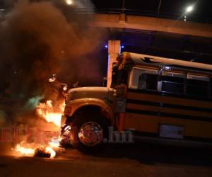 Un autobús cruza neumáticos en llamas que bloquean una carretera en Tegucigalpa. Foto: Agencia AFP.