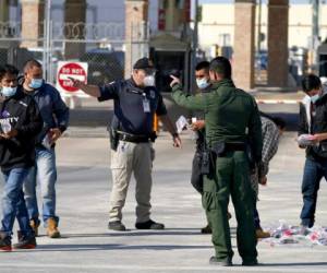 Agentes del servicio de Aduanas y Protección de Fronteras dan indicaciones a migrantes que están siendo deportados, enviados de vuelta a México, en el Puente Internacional McAllen-Hidalgo. Foto: AP.