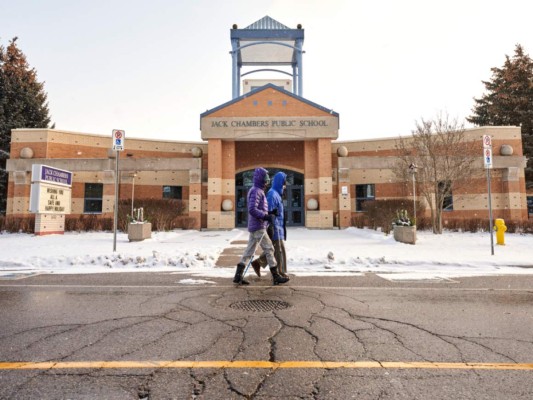 Una pareja pasa por la Escuela Pública Jack Chambers en London, Ontario, el 6 de enero de 2022, el día después de que la provincia de Ontario hizo la transición al aprendizaje en línea frente a la variante Omicron de Covid-19 de rápida propagación. Foto: Agencia AFP.