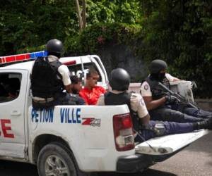 La policía lleva a dos detenidos a la comisaría de policía de Petion Ville en Puerto Príncipe, Haití, el jueves 8 de julio de 2021. Según el jefe de policía Leon Charles, los dos detenidos son sospechosos del asesinato del presidente haitiano Jovenel Moïse. Foto: AFP