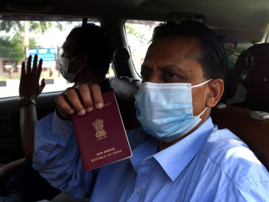 Un personal policial revisa el pasaporte de los funcionarios de la Alta Comisión de la India dirigidos a una instalación de cuarentena en medio de la preocupación por la propagación del coronavirus. Foto: Agencia AP.