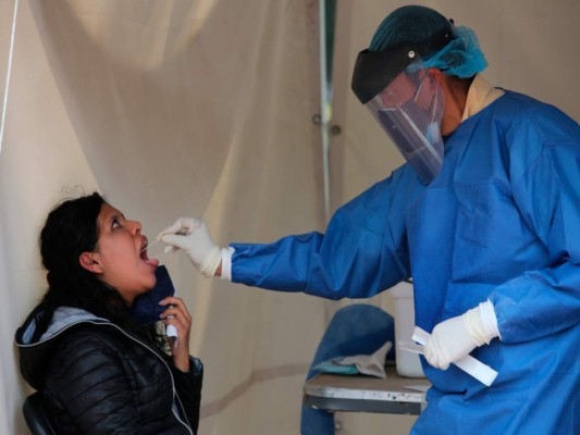 Un trabajador de la salud toma una muestra de la garganta de una mujer para hacer una prueba de detección de COVID-19 en Ciudad de México el sábado 10 de julio de 2021. (AP Foto/Ginnette Riquelme).
