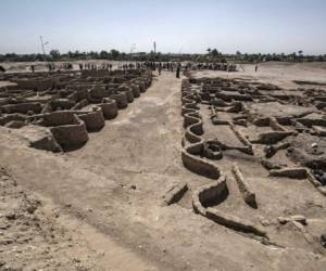 A picture taken on April 10, 2021, shows workers standing next to a display of artifacts uncovered at the archaeological site of a 3000 year old city, dubbed The Rise of Aten, dating to the reign of Amenhotep III, uncovered by the Egyptian mission near Luxor. - Archaeologists have uncovered the remains of an ancient city in the desert outside Luxor that they say is the 'largest' ever found in Egypt and dates back to a golden age of the pharaohs 3,000 years ago. Famed Egyptologist Zahi Hawass announced the discovery of the 'lost golden city', saying the site was uncovered near Luxor, home of the legendary Valley of the Kings. (Photo by Khaled DESOUKI / AFP)