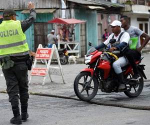 Un oficial de policía detiene a dos hombres en una motocicleta en Tumaco, municipio del departamento colombiano de Nariño, cerca de la frontera con Ecuador, tomada el 16 de abril de 2018 días después de que se reforzó la presencia militar tras el asesinato de un equipo de periodistas ecuatorianos en el área. (AFP)