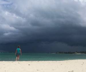 Una mujer camina en la playa cuando se acerca una tormenta en Nassau, Bahamas. Foto: Agencia AFP.