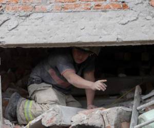 Un trabajador de rescate busca a un sobreviviente atrapado en el sitio de un edificio de apartamentos de gran altura, del cual se derrumbaron los primeros cuatro pisos, en el barrio de Linda Vista de la Ciudad de México. Agencia AP.
