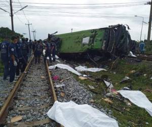 Rescatistas junto a un vehículo dañado y varios cuerpos cubiertos de sábanas blancas, tras una colisión entre un autobús y un tren en la provincia de Chacheongsao, 80 kilómetros (50 millas) al este de Bangkok, Tailandia, el domingo 11 de octubre de 2020. Foto: AP
