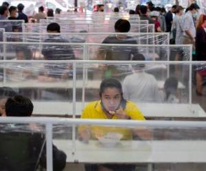 Clientes comen en un patio de comidas en mesas comunes separadas por pantallas de plástico en Bangkok, Tailandia, 19 de mayo de 2020. Tailandia empieza a mitigar las restricciones del coronavirus. (AP Foto/ Gemunu Amarasinghe)