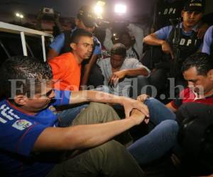 José Luis López Flores (camisa naranja), José Alberto Ponce Cáceres (azul) y Ángel Antonio Velásquez Enamorado (rojo), al momento de ser trasladados en una patrulla en Tegucigalpa. Los sujetos fueron capturados en el marco de la Operación Panamericano para desmantelar una banda de trasiego de drogas integrada por policías (Foto: David Romero/ El Heraldo Honduras/ Noticias de Honduras).