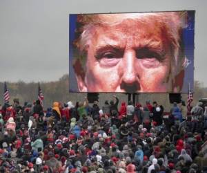 Partidarios del presidente Donald Trump miran una pantalla de video en un evento de campaña el 27 de octubre de 2020 en Lansing, Michigan. (Nicole Hester/Mlive.com - Ann Arbor News via AP).