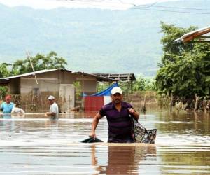 Habitantes de Pimienta, Cortés, al norte de Honduras, tratan de salvar algunas pertenencias de sus viviendas anegadas.