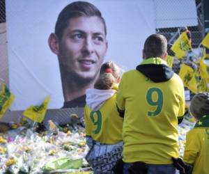 Los aficionados rinden homenaje y miran las flores amarillas que se exhiben ante el retrato del delantero argentino Emiliano Sala en el estadio Beaujoire de Nantes. Foto AFP