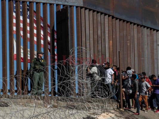 Los migrantes centroamericanos observan una valla fronteriza como una parada parroquial fronteriza de EE. UU. En el cruce fronterizo de El Chaparral en Tijuana, estado de Baja California, México. Agencia AFP.