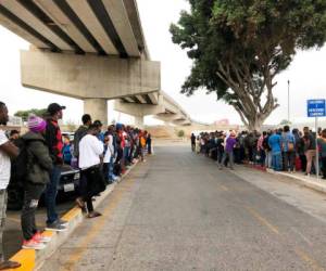Decenas de migrantes escuchan expectantes en Tijuana, México, los nombres de quienes son llamados para que puedan iniciar una solicitud de asilo en Estados Unidos. Foto: Agencia AP.