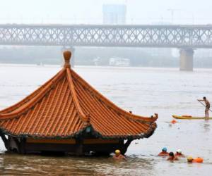 Residentes nadan junto al un pabellón sumergido por la crecida del río Yangtsé en Wuhan, en el centro de China. Socorristas buscaban el miércoles a nueve personas desaparecidas en un alud, en medio de inundaciones en gran parte del país. (Chinatopix Via AP)
