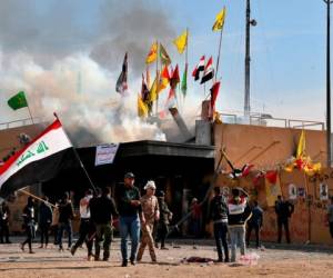 Milicianos proiraníes y sus partidarios provocan un incendio mientras soldados estadounidenses lanzan gases lacrimógenos durante una sentada ante la embajada de Estados Unidos en Bagdad, Irak, el 1 de enero de 2020.