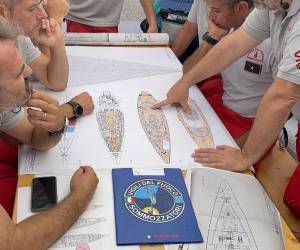 La Guardia Costera italiana evalúa la seguridad de entrar en la embarcación mientras continúa la operación de búsqueda. Entre los rescatados están una niña de un año y su madre.