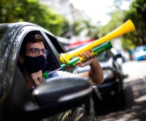 Un manifestante grita 'Fuera, Bolsonaro' mientras usa un generador de ruido durante una caravana en contra del manejo del gobierno de la pandemia de covid-19 y para exigir la destitución del presidente brasileño Jair Bolsonaro en Río de Janeiro, Brasil, el sábado 23 de enero de 2021. Foto: AP