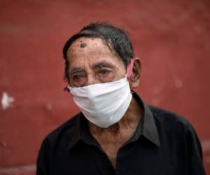 En esta imagen, tomada el 31 de marzo de 2020, Ciro Orlando Gijón, de 78 años y con mascarilla por el coronavirus, espera para solicitar una plaza en el albergue habilitado en la plaza de toros de Acho, en Lima, Perú.