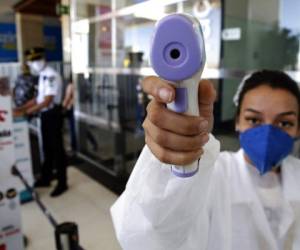 Una mujer toma la temperatura a un fotógrafo en un centro comercial de Brasilia. Foto: AP.