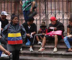 Un grupo de migrantes sentado en las gradas de la catedral metropolitana de Tegucigalpa. El centro de la capital está lleno de migrantes irregulares que piden dinero a los transeúntes.