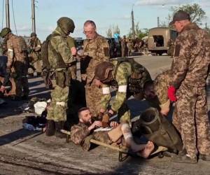 Esta captura de pantalla obtenida de un video informativo publicado por el Ministerio de Defensa de Rusia el 17 de mayo de 2022 muestra a miembros del servicio ucranianos mientras son registrados por personal militar prorruso después de salir de la planta siderúrgica Azovstal sitiada en la ciudad portuaria de Mariupol en Ucrania.